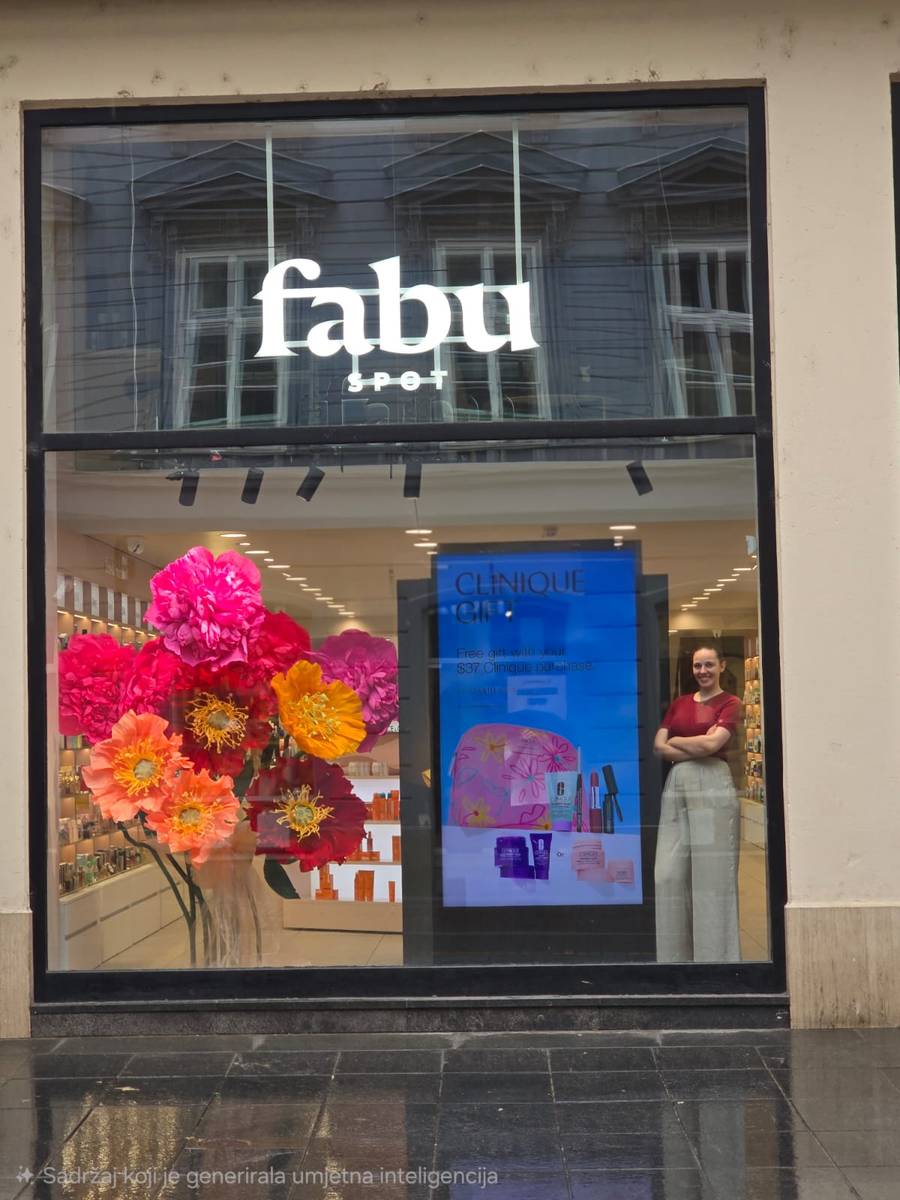 Petra u izlogu Fabu Spot parfumerije s velikim papirnatim cvijećem